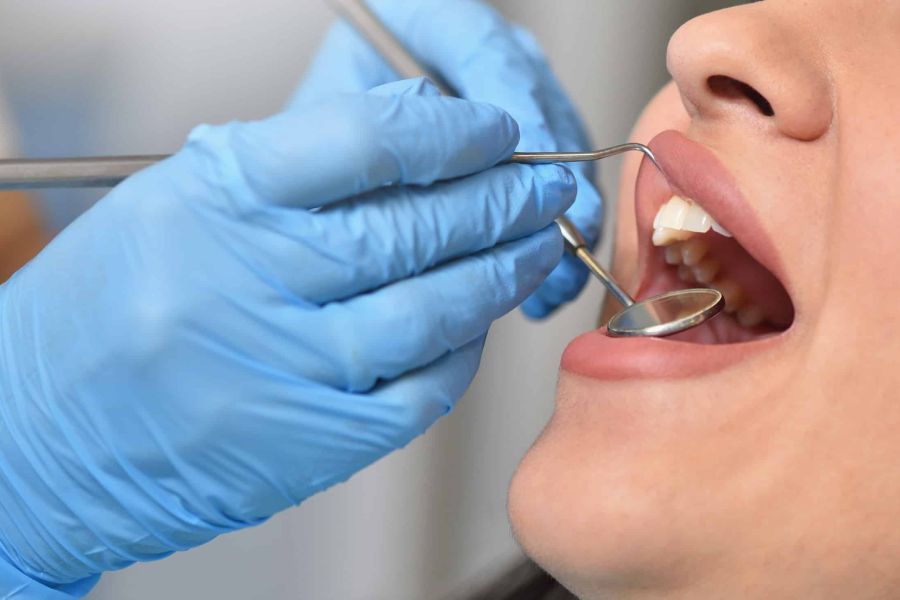 Zahnarzt untersucht das Zahnfleisch einer Patientin